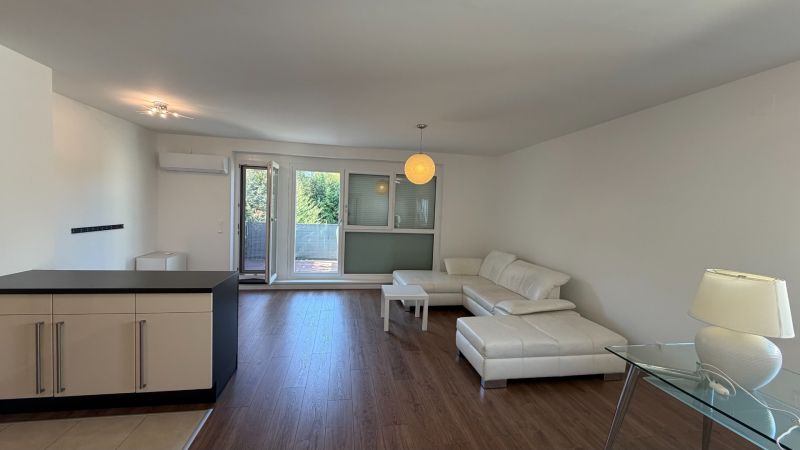 Living room in a 3-room apartment with a white sofa and a floor with a wooden decor.