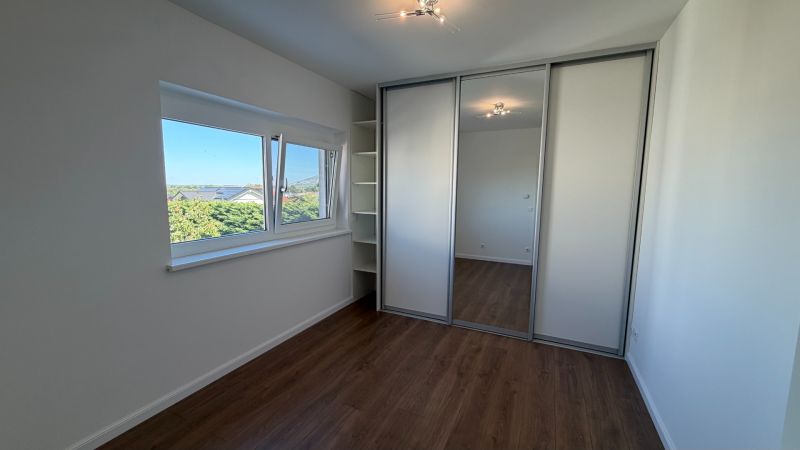 A room in a 3-room apartment with a wood-patterned floor and a built-in wardrobe.