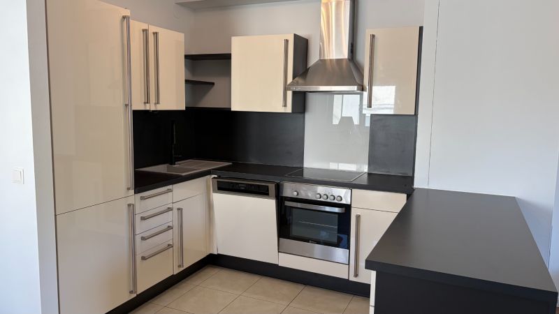 A kitchen in a 3-room apartment, with matching black and white kitchen cabinets and appliances.