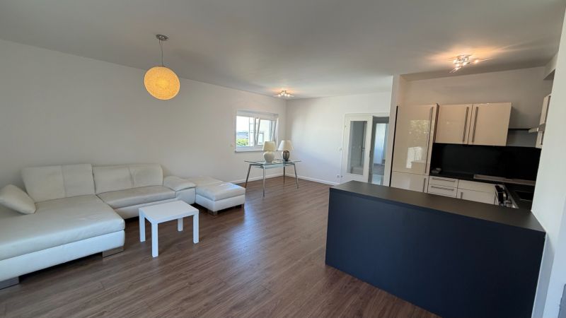 Living room in a three-room apartment with a white sofa and a wooden decor floor.