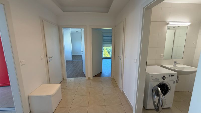 In the interior of a 3-room apartment with a wooden decor floor and a washing machine in the bathroom.
