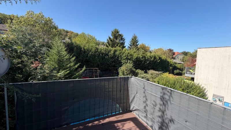 Terrace of a 3-room apartment in Wolfsthal with a view of greenery and blue sky.