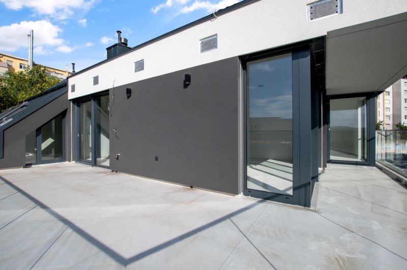 Spacious terrace of a 5 or more room apartment with a modern facade and glass railing.