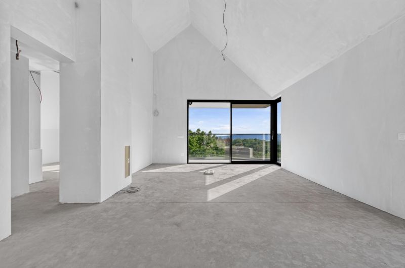 A spacious living room with large windows in a 5 or more room apartment and a view of nature.