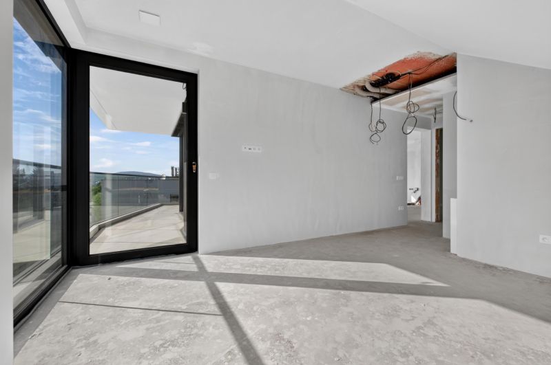 An interior with an unfinished floor and glass doors in a 5 or more room apartment.