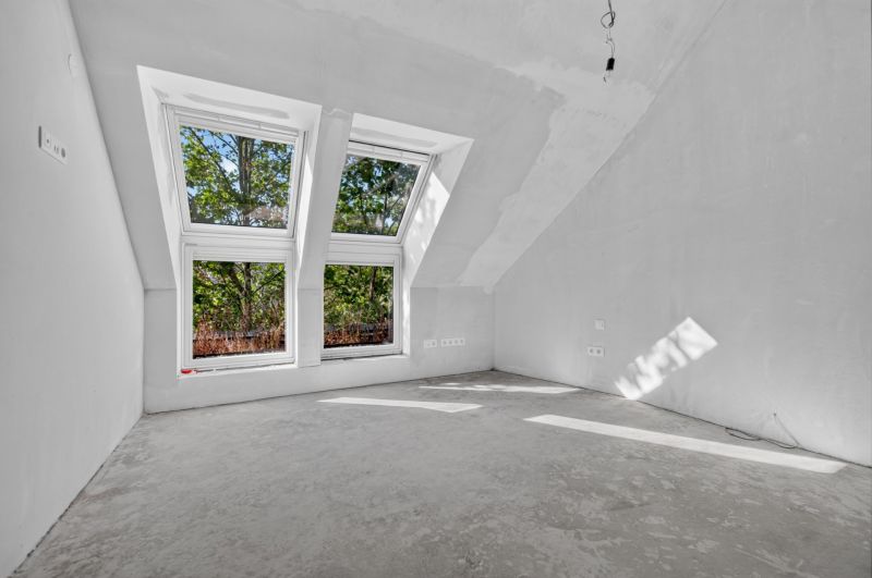 An attic room in a 5 or more room apartment with large skylights without flooring.