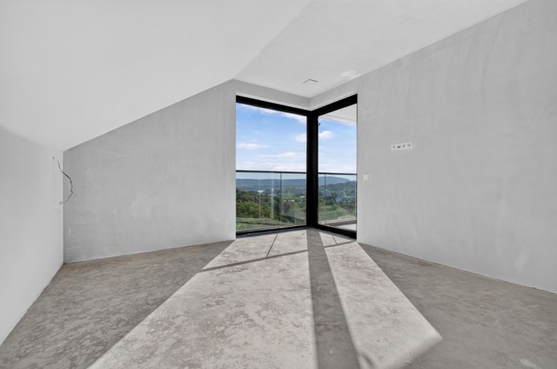 A spacious room in a 5 or more bedroom apartment with large windows and a concrete floor.