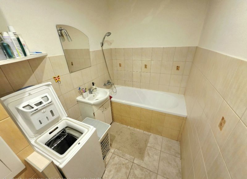 A bathroom with a stove washing machine, bathtub, and sink in a 4-room apartment.