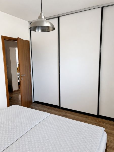 A bedroom in a 3-room apartment with a lamp, a wardrobe, and a wooden decor floor.