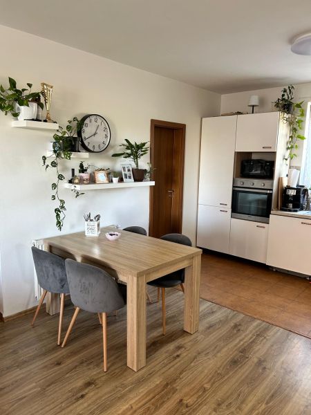 A kitchen in a 3-room apartment with wall shelves and a wooden decor floor.