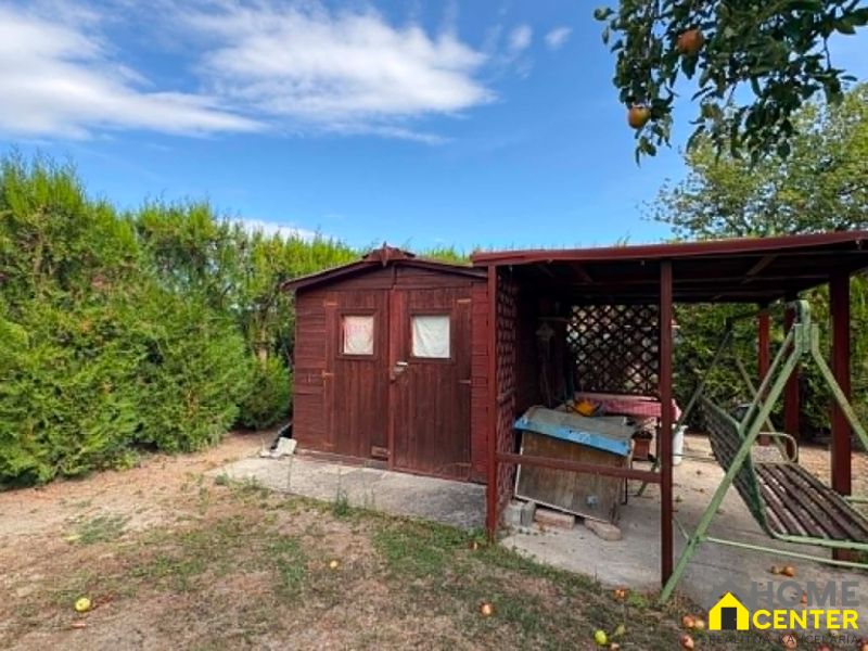 A wooden gazebo and a swing in the garden in Komárno with fruit trees.