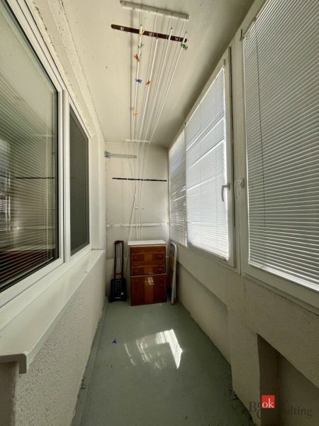 A glazed balcony with a wooden cabinet and a drying rack, part of a studio apartment.