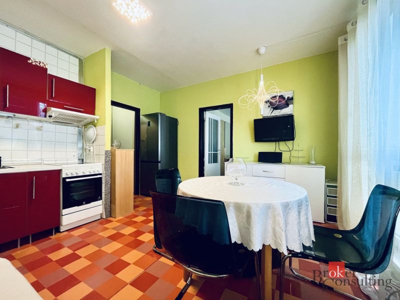 A kitchen in a studio apartment with colorful tiles, red cabinets, and a round table.