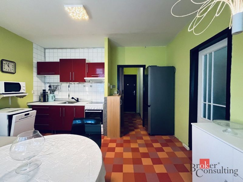 A kitchen in a studio apartment with colorful tiles, white tiles, and green walls.