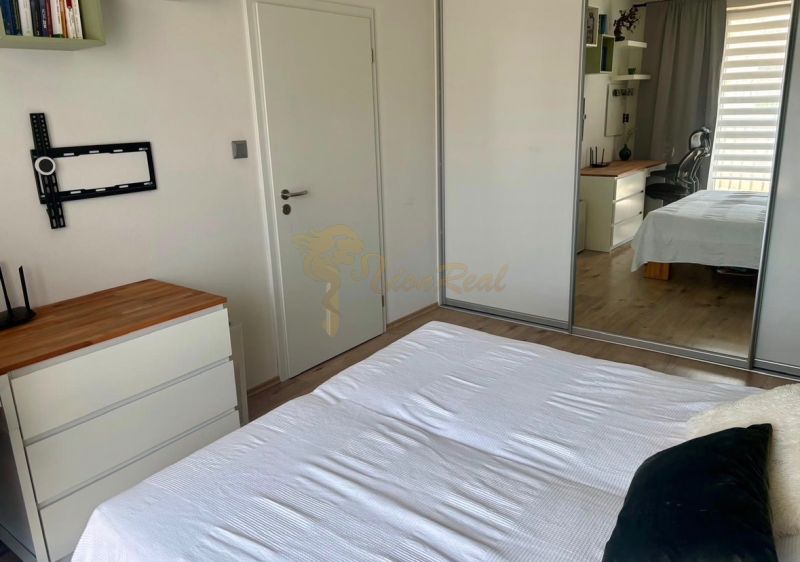 Bedroom in a 2-room apartment with a white bed and a wooden decor floor.