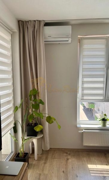 A room with a wooden floor decor, plants, and air conditioning in a 2-room apartment.