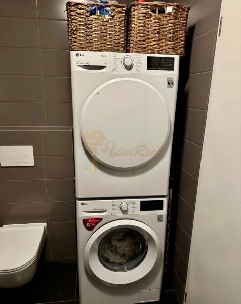 Bathroom in a 2-room apartment with an LG washer and dryer, laundry baskets.