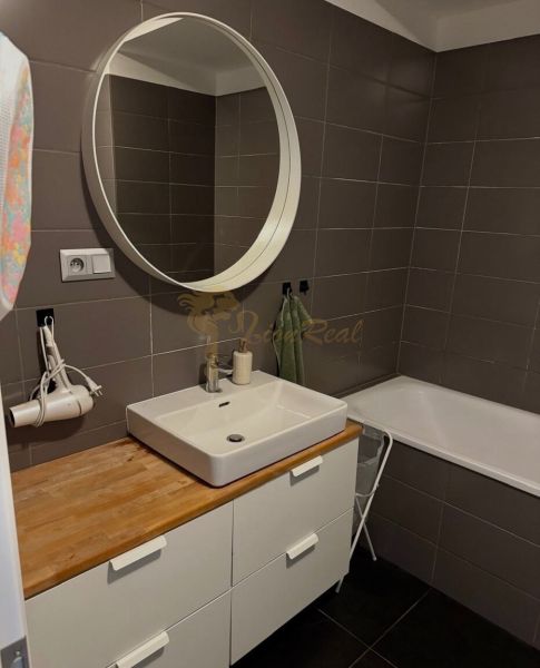 Bathroom in a 2-room apartment with a sink, mirror, and bathtub, elegant brown tiles.
