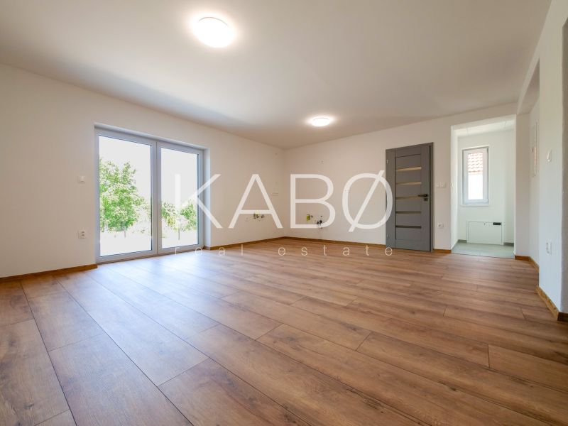 Living room in a family house with large windows and wooden decor flooring.