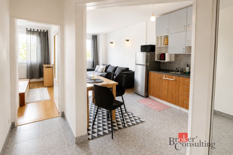 Interior of a 2-room apartment with a kitchen, living room, and wooden decor flooring.