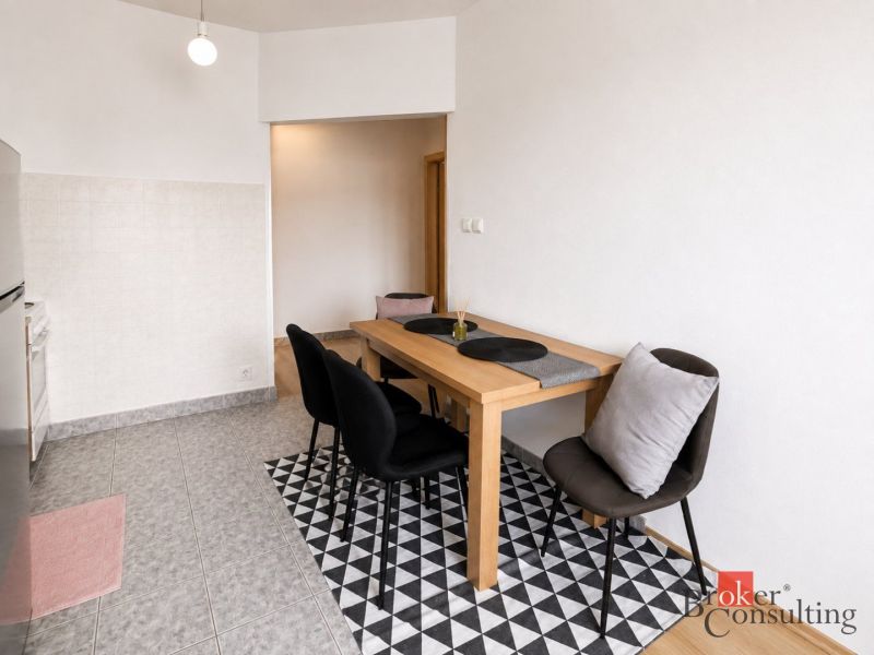 Dining area in a 2-room apartment with black chairs and a wooden table.