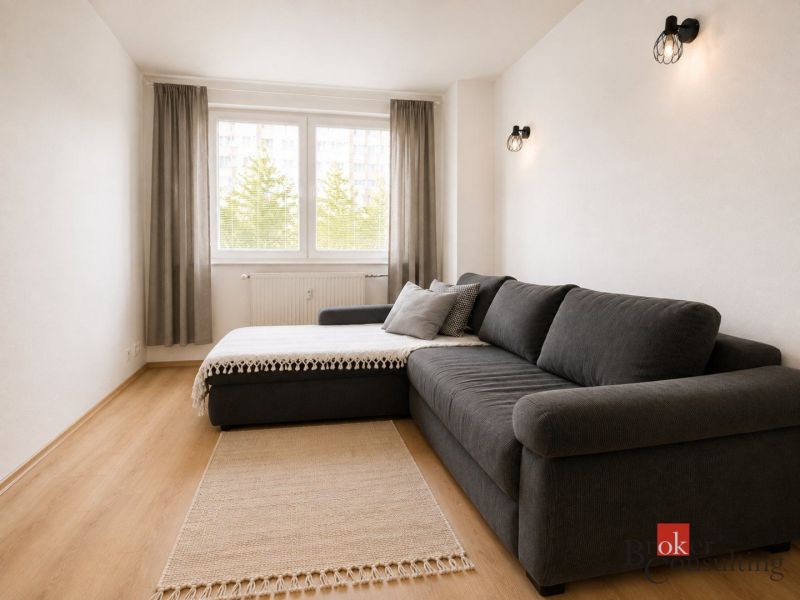 Living room in a 2-bedroom apartment with a comfortable sofa and a floor with a wooden design.
