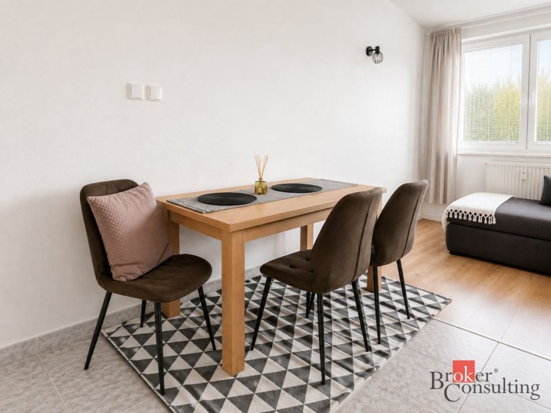 Dining area with a table and chairs in a 2-room apartment, with a wooden decor floor.