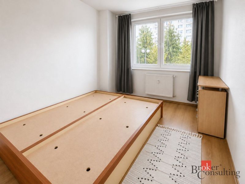 Bright bedroom in a 2-room apartment with a bed and wood-patterned flooring.