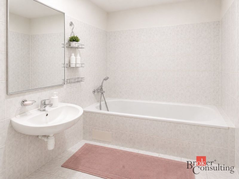 A bathroom in a 2-room apartment with a bathtub, sink, and light-colored tiles.
