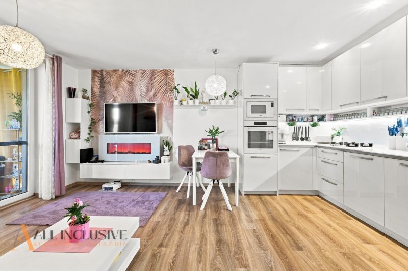Living room in a family house with a kitchen, white furniture, and a wooden decor floor.