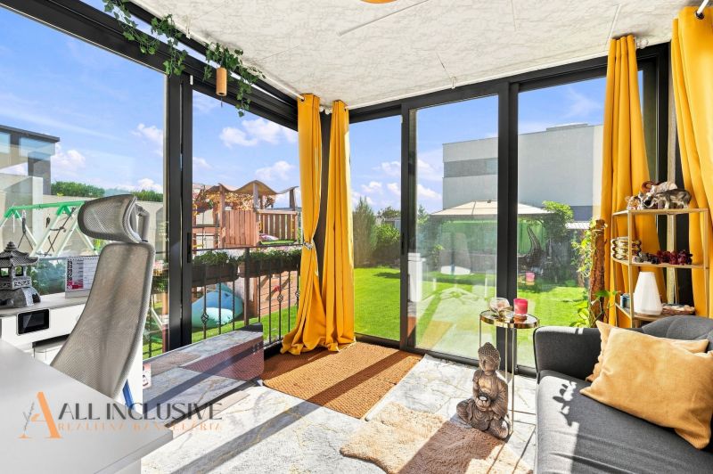 A sunny room in a family house with a view of the garden through glass doors.