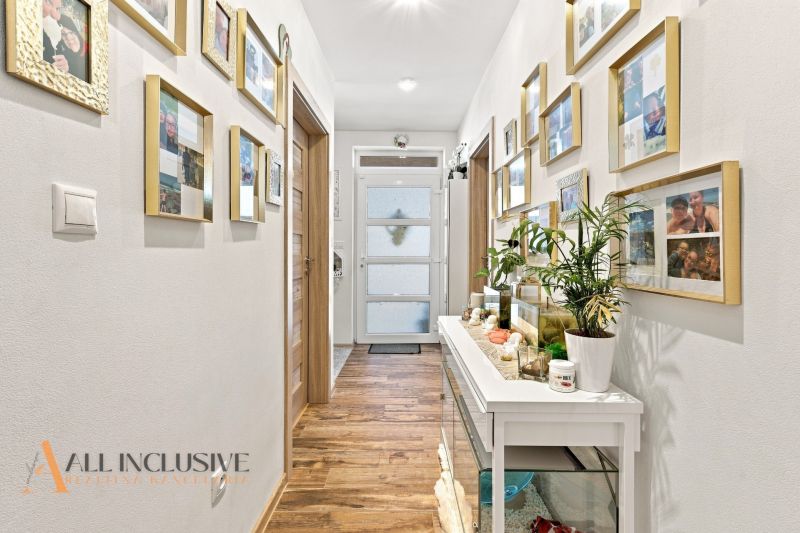 A hallway of a family house with a wooden decor floor and a lot of family photographs.