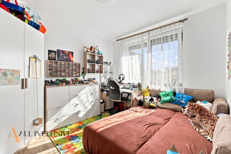 Children's room in a family house with toys, a patterned carpet, and a desk.