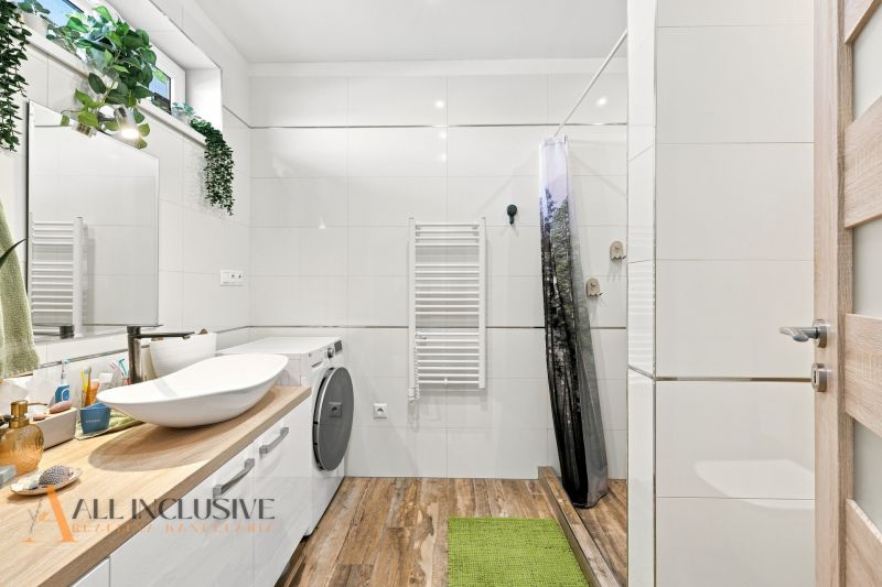 A bathroom in a family house with wooden floor decor and a washing machine.