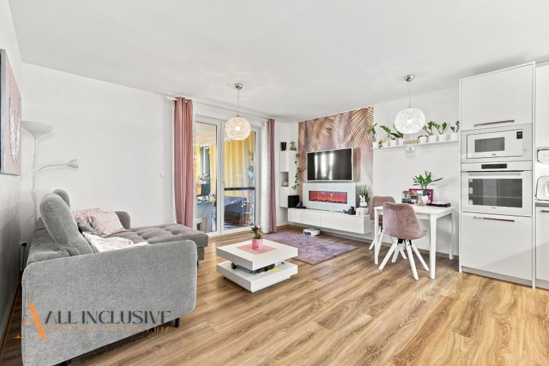 Living room with a comfortable sofa, TV, dining table, and wooden decor flooring in a family house.