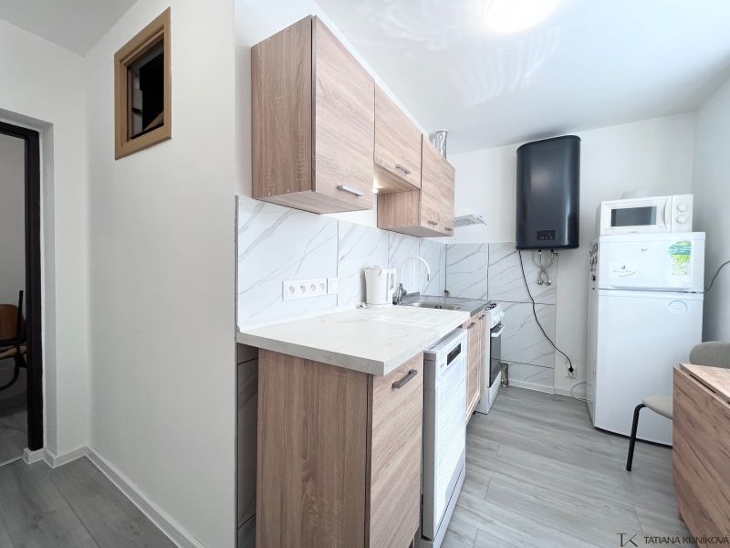 A kitchen in a 3-room apartment with a wood-patterned floor and white appliances.