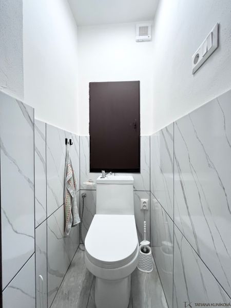 WC in a 3-room apartment with marble tiles and white sanitary ware.