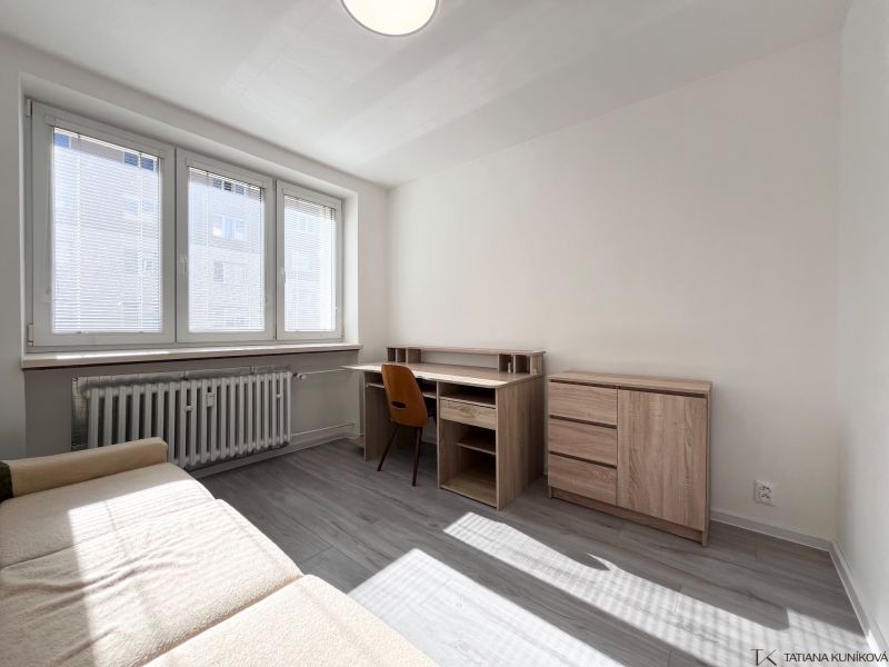 Living room with a desk and a sofa, wooden decor flooring in a 3-room apartment.