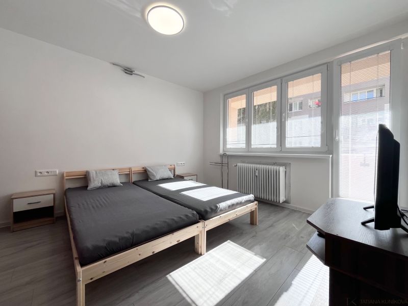 A bright bedroom with a bed, TV, and wooden decor flooring in a 3-room apartment.