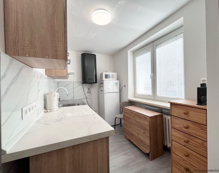 A kitchen in a 3-room apartment with tiles and wooden cabinets.