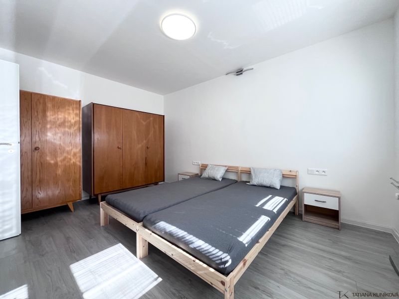 A bedroom with a bed, wooden wardrobes, and a floor with a wooden decor in a 3-room apartment.