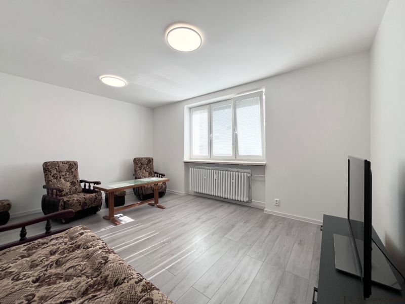 Living room in a 3-room apartment with furniture, a television, and a wooden decor floor.