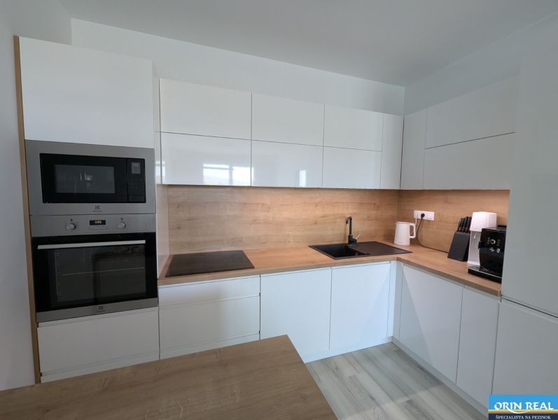 A kitchen in a 2-room apartment with a wooden decor floor and modern appliances.
