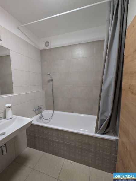 A bathroom in light tones with a bathtub and a shower, ideal for a 2-room apartment.
