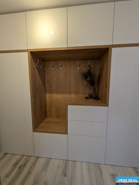 White built-in wardrobe with wood decor and hangers in a 2-room apartment.