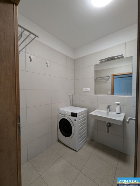 A bathroom with a washing machine and a sink in a 2-room apartment.