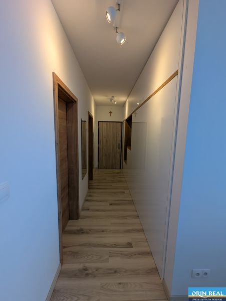 A hallway in a 2-room apartment with a wooden decor floor and white walls.