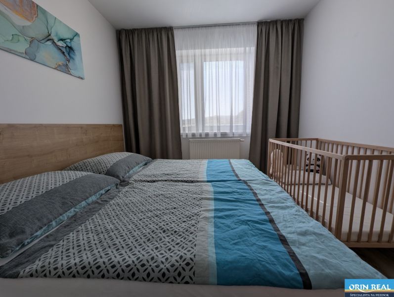 A bright bedroom with a bed and a crib in a 2-room apartment.