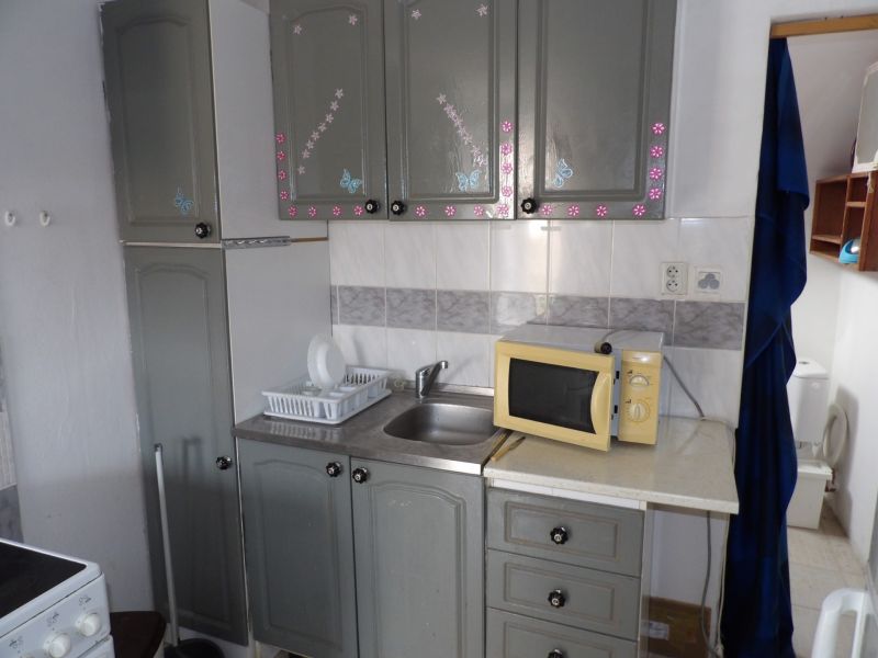 Kitchen area in a 2-room apartment with a microwave and decorated cabinets.