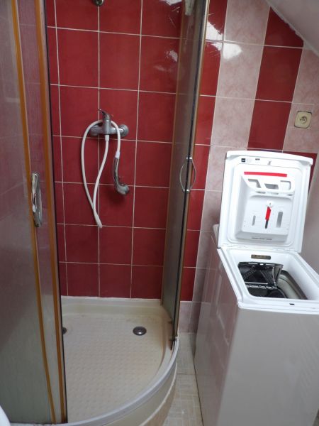 A shower enclosure in the bathroom of a 2-room apartment, with a washing machine installed.